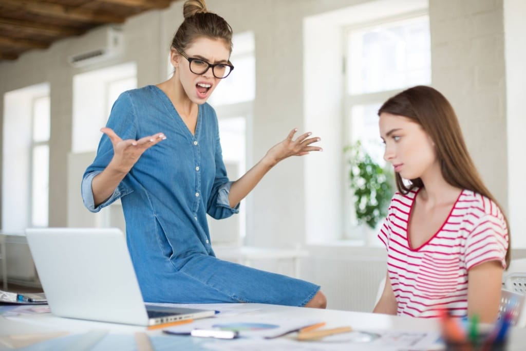 angry business woman in eyeglasses leaning on desk while screaming on employee in modern office 1920x1280